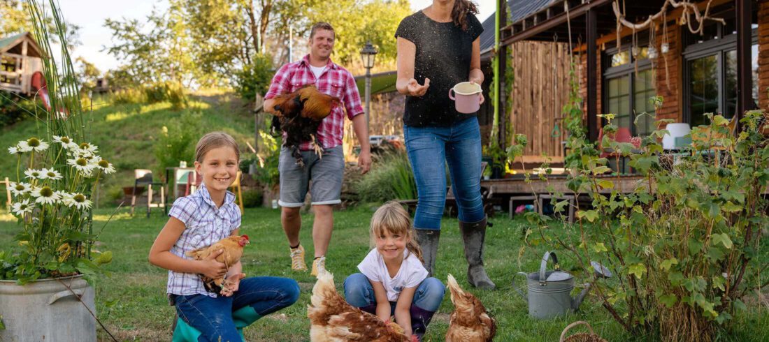 Eine junge Familie füttert Hühner im Garten