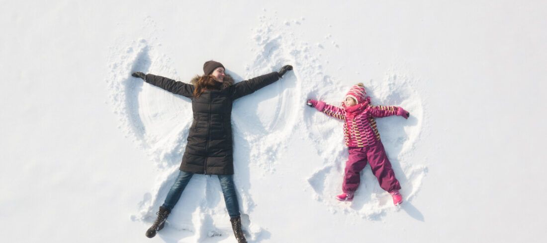 Das Weihnachtsmotiv der Einfach Ankommen Kampagne zeigt Mutter und Kind, die unbeschwert einen Schneeengel kreieren.